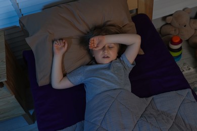 Photo of Little boy snoring while sleeping in bed at night, above view
