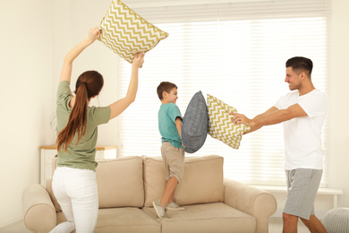 Photo of Happy family having pillow fight in living room