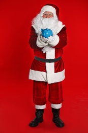 Photo of Santa Claus holding piggy bank on red background