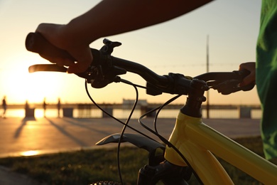 Young woman with bicycle on city waterfront at sunset, closeup