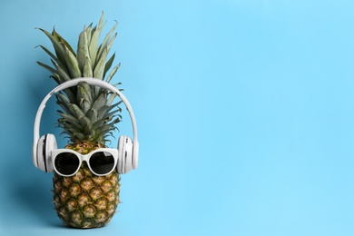 Pineapple with sunglasses and headphones on light blue background, space for text. Creative concept