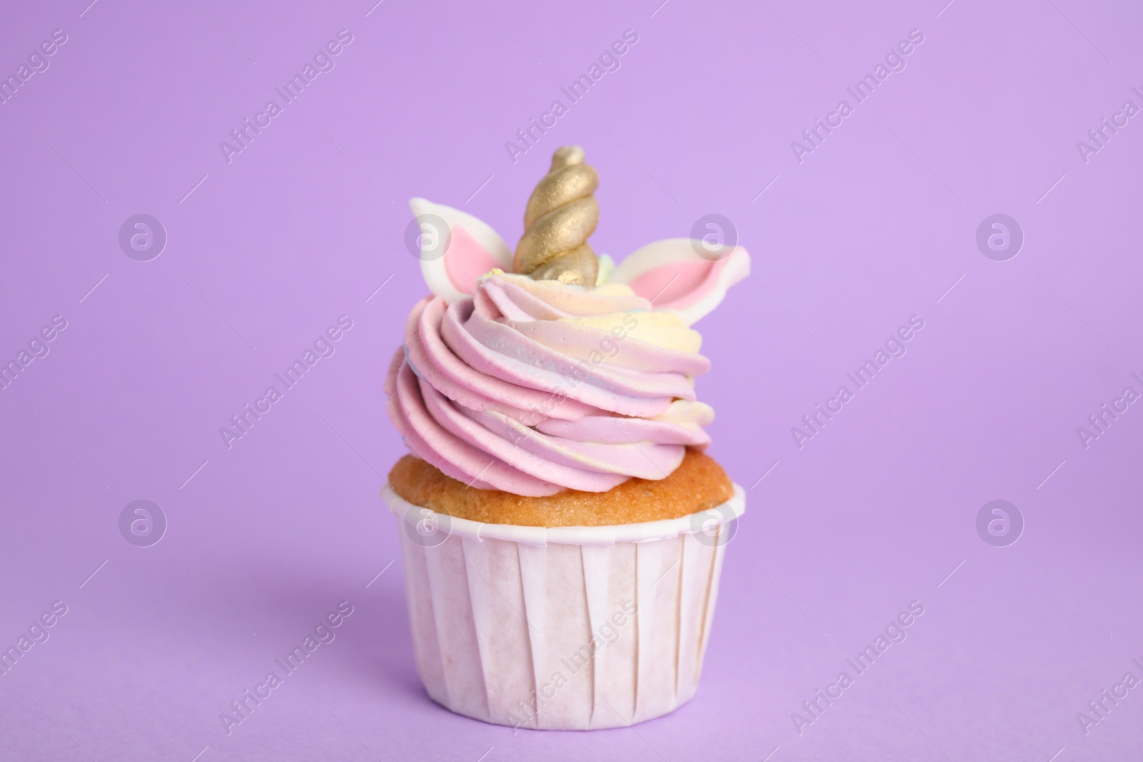 Photo of Cute sweet unicorn cupcake on violet background