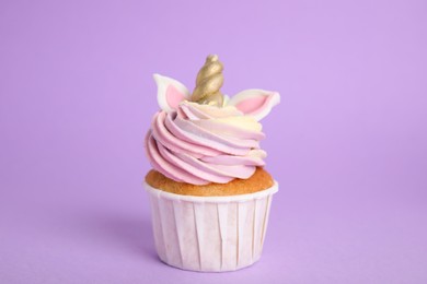 Photo of Cute sweet unicorn cupcake on violet background