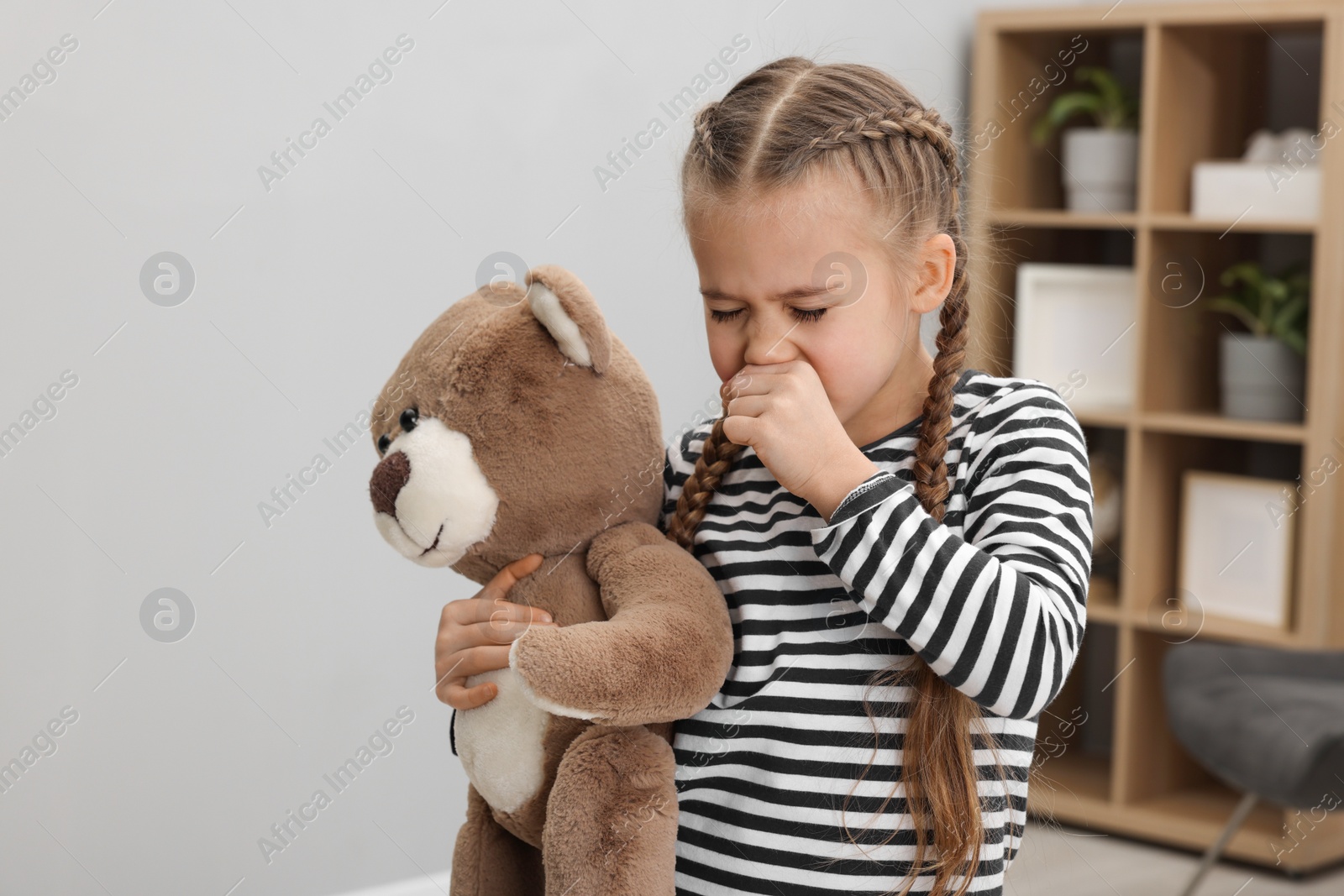 Photo of Sick girl with teddy bear coughing at home