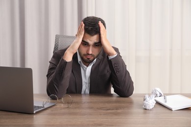 Tired sad businessman sitting at table in office