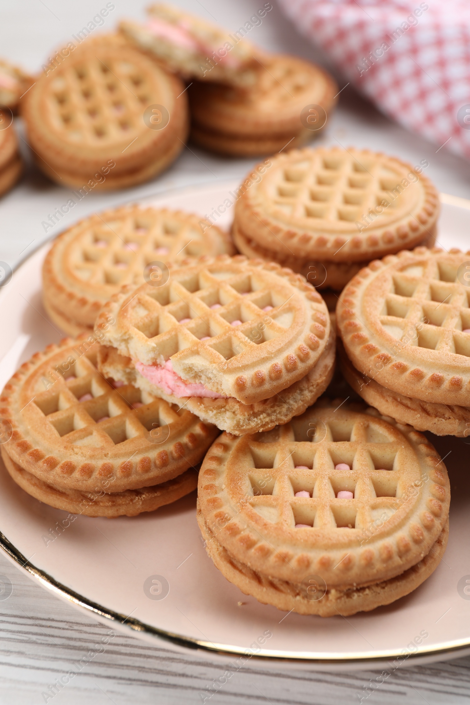 Photo of Tasty sandwich cookies with cream on white wooden table, closeup