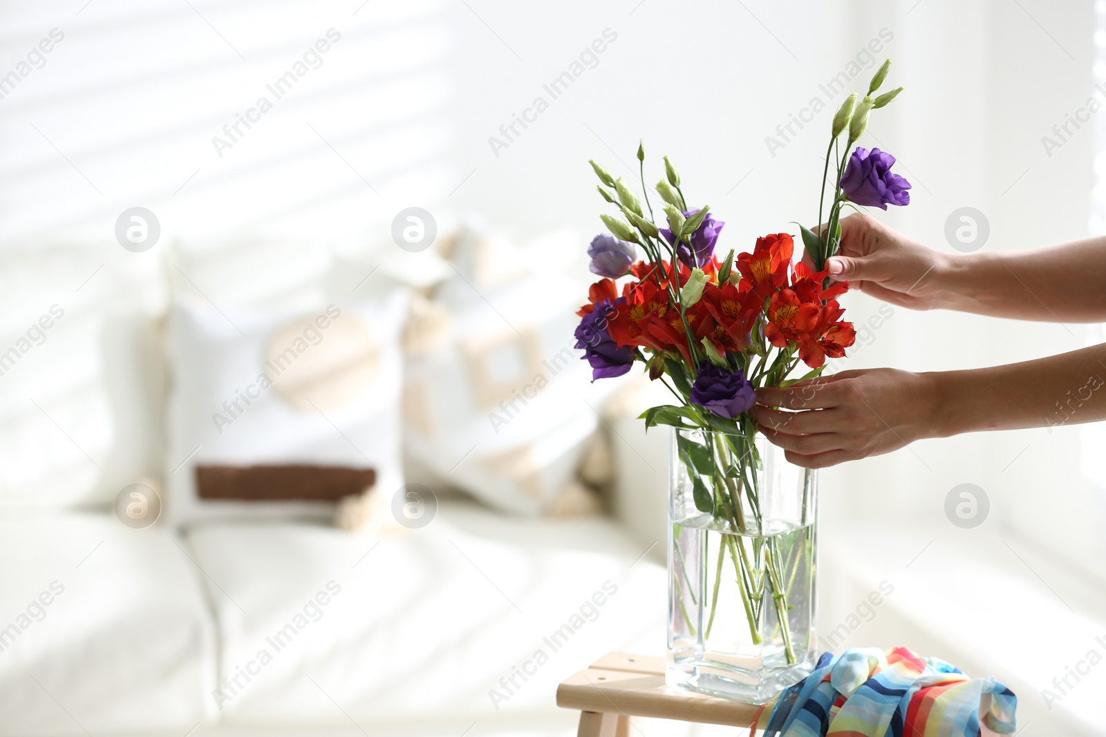 Photo of Woman and vase with beautiful flowers on wooden table in room, closeup. Space for text