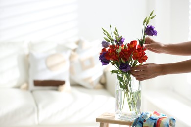 Woman and vase with beautiful flowers on wooden table in room, closeup. Space for text
