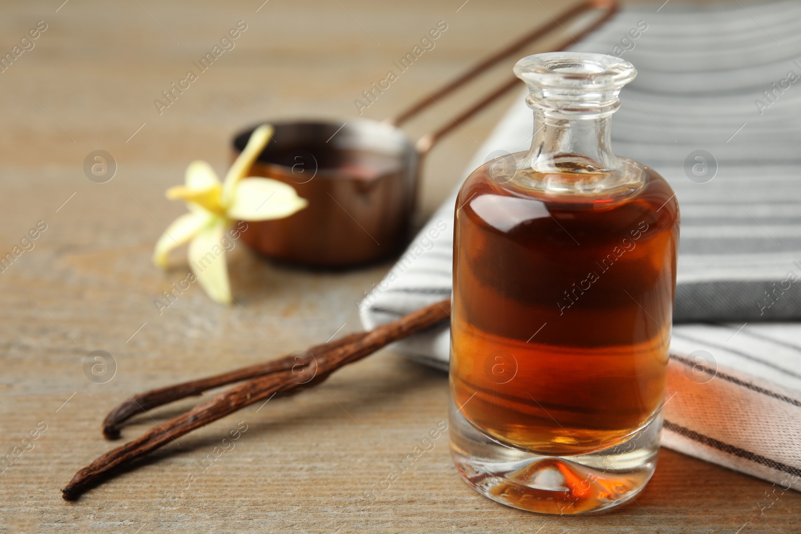 Photo of Aromatic homemade vanilla extract on wooden table, closeup. Space for text