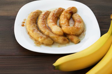 Photo of Delicious fried and fresh bananas on wooden table, closeup