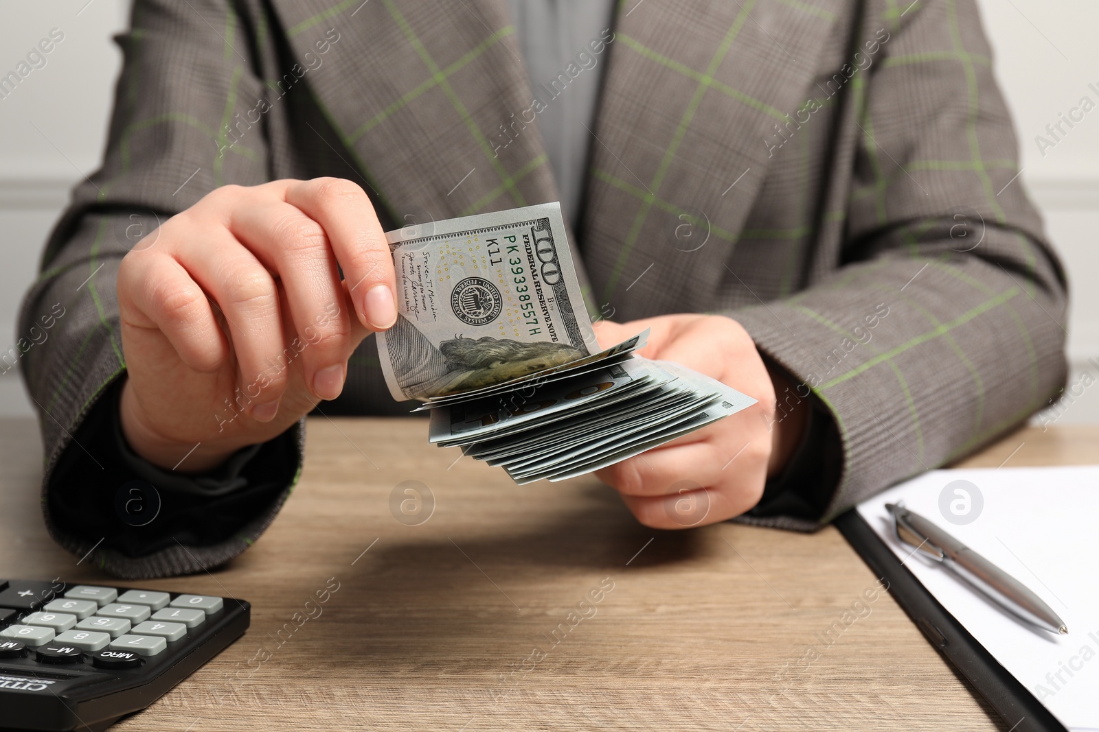 Photo of Money exchange. Woman counting dollar banknotes at wooden table, closeup