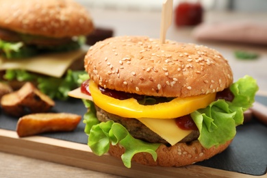 Board with delicious hamburger on table. Space for text