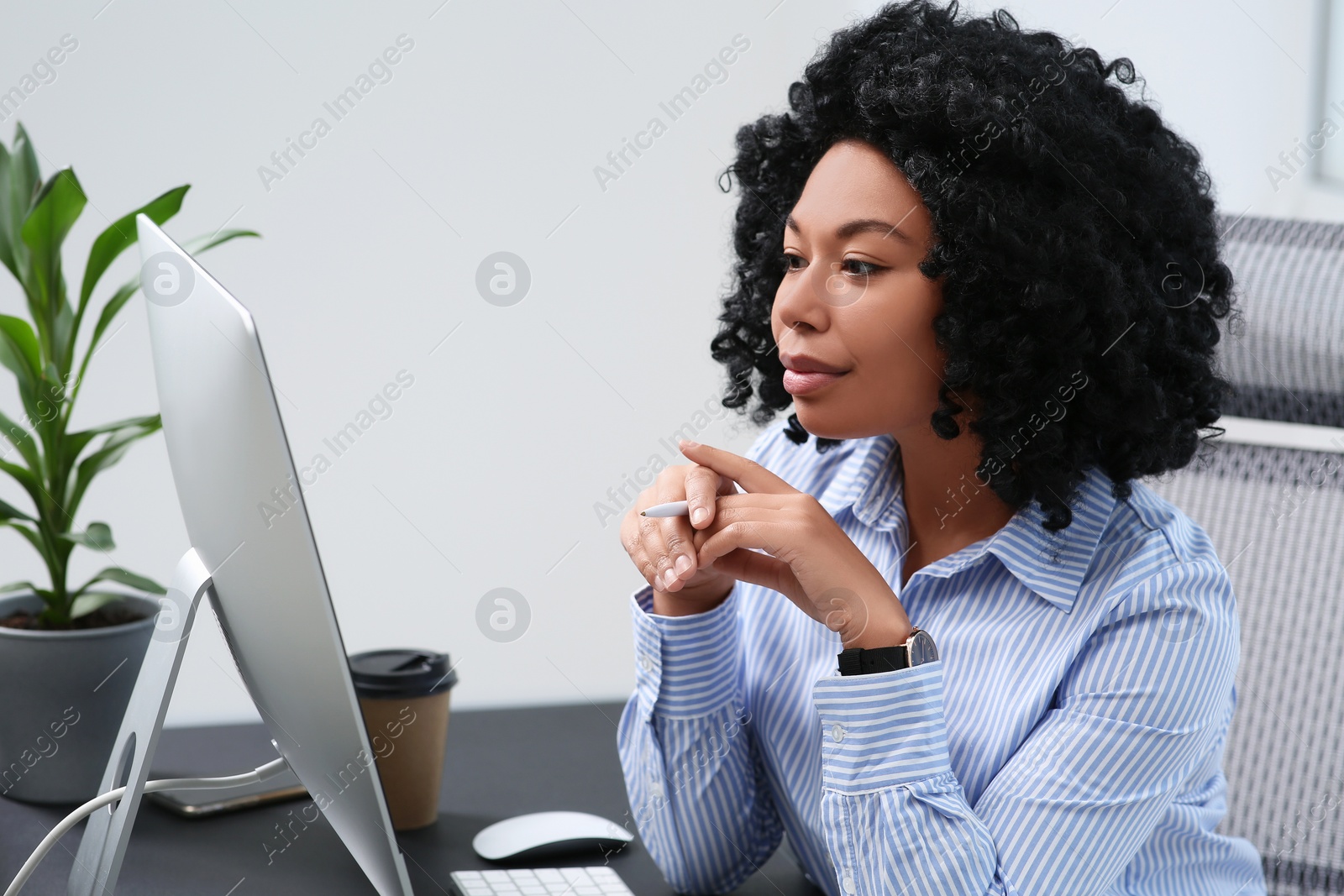 Photo of Young woman working on computer at table in office