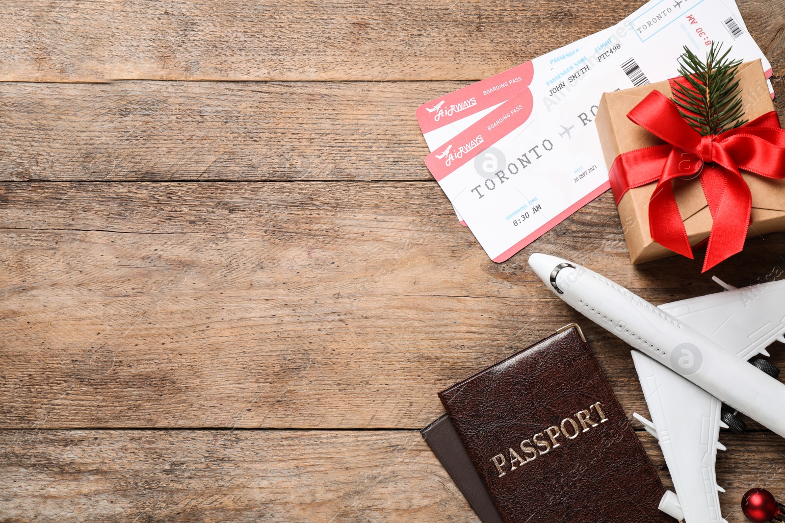 Photo of Flat lay composition with airline tickets, toy plane and passports on wooden table, space for text. Christmas vacation