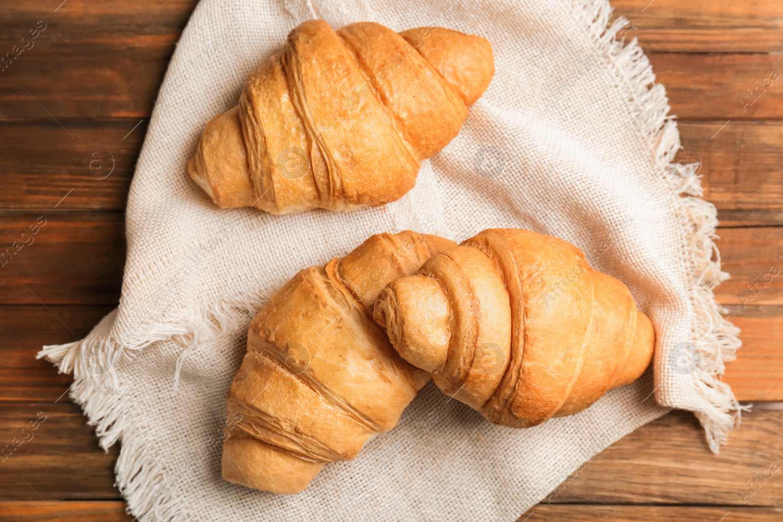 Photo of Tasty croissants on wooden background, top view