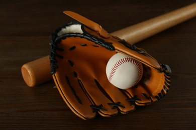 Photo of Leather baseball ball, bat and glove on wooden table