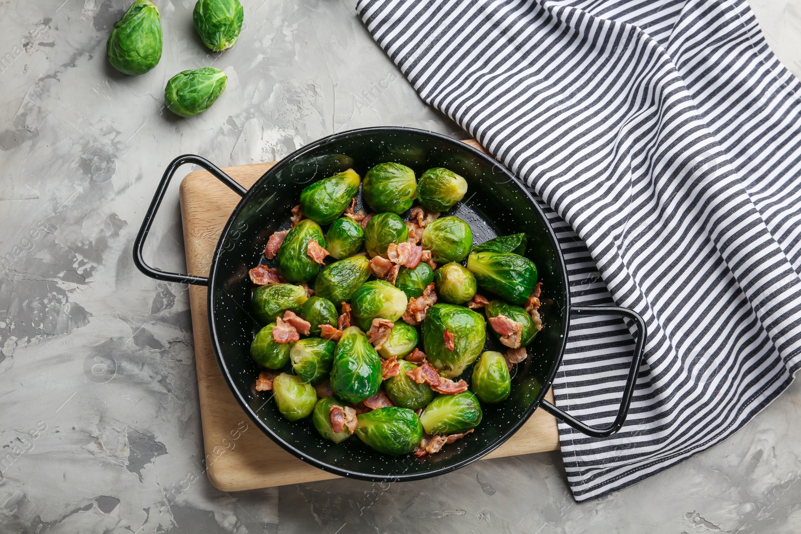 Photo of Tasty roasted Brussels sprouts with bacon on light grey table, flat lay