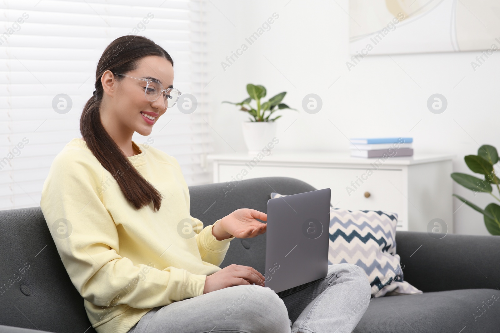 Photo of Woman having video chat via laptop on couch at home