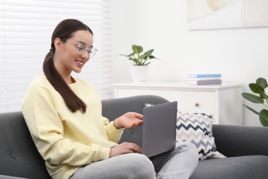 Woman having video chat via laptop on couch at home