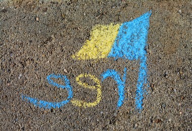 Photo of National flag of Ukraine with word Free drawn by blue and yellow chalk on asphalt, top view