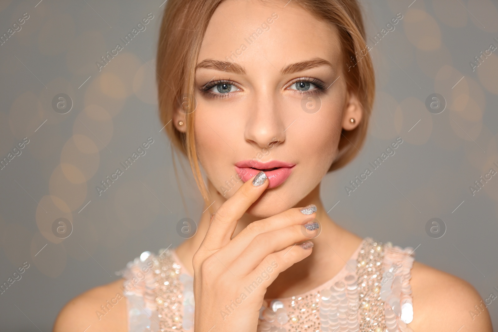 Photo of Beautiful young woman with shiny manicure on blurred background, closeup. Nail polish trends