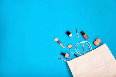 Photo of Stylish flat lay composition with shopping bag and cosmetics on color background