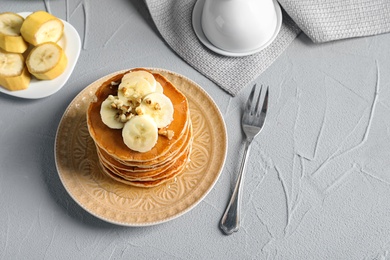 Stack of tasty pancakes with banana, nuts and honey on table