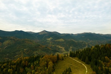 Image of Aerial view of beautiful mountain forest with countryside road on autumn day