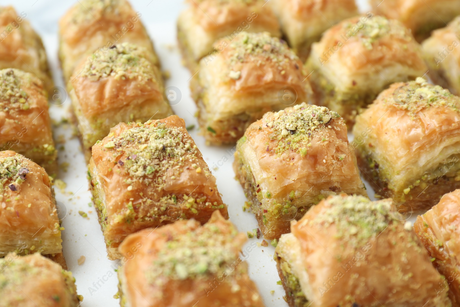 Photo of Delicious fresh baklava with chopped nuts on white table, closeup. Eastern sweets