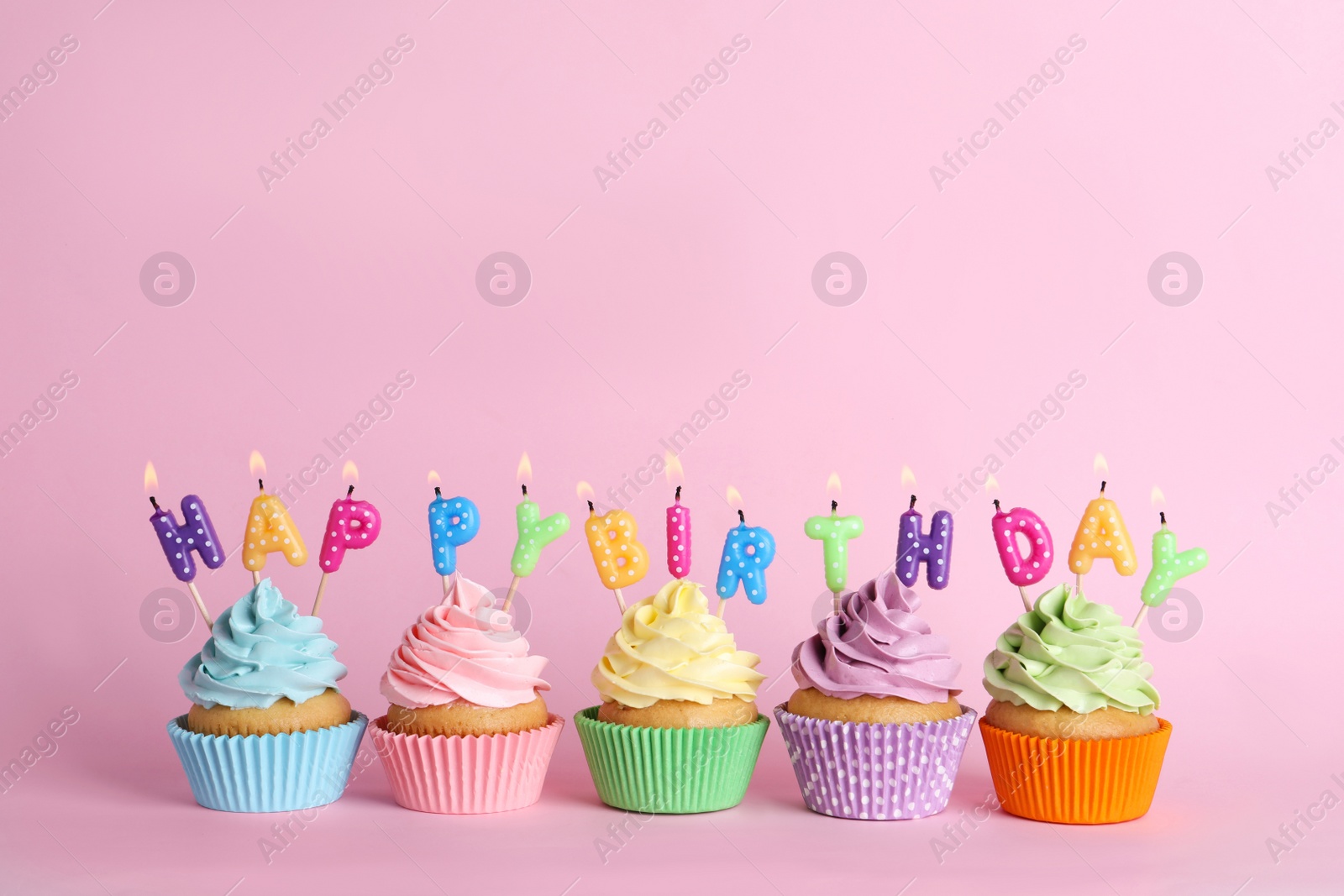 Photo of Birthday cupcakes with burning candles on pink background