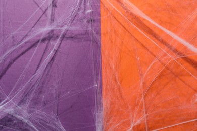 Creepy white cobweb hanging on color background