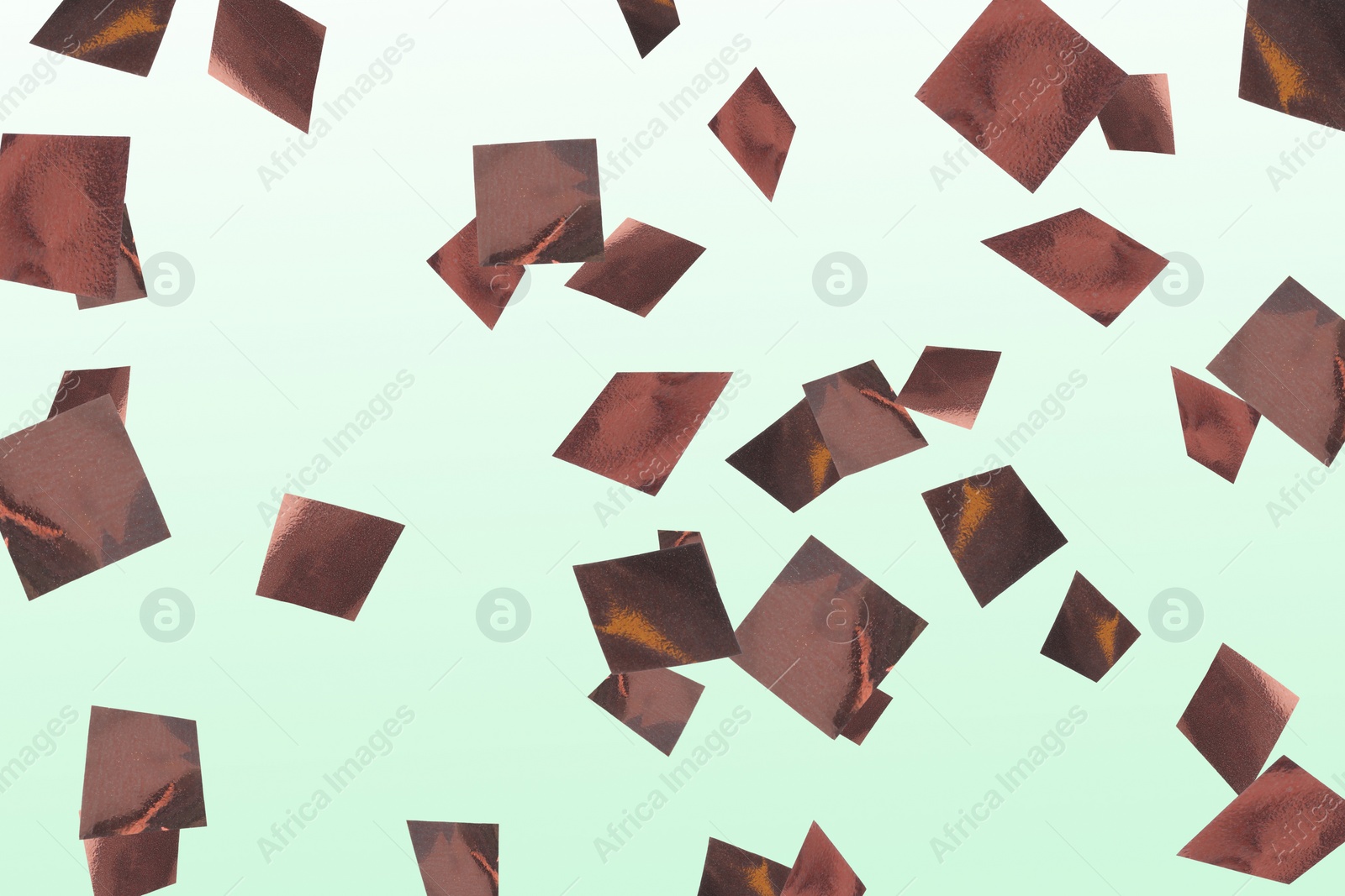 Image of Shiny bronze confetti falling on light green background