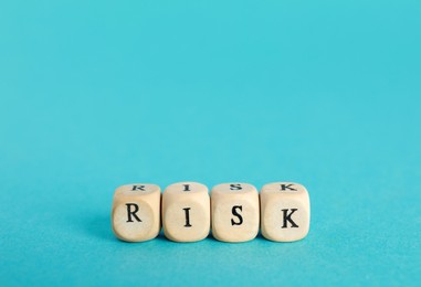 Photo of Word Risk made of small wooden cubes on turquoise background