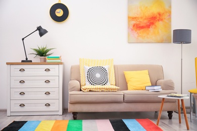 Photo of Modern room interior with comfortable sofa and rainbow carpet