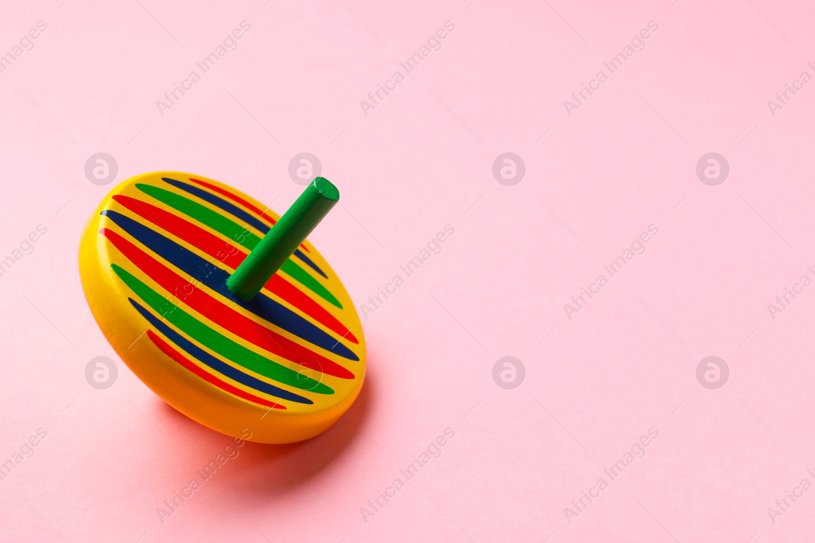 Photo of One colorful spinning top on pink background, space for text