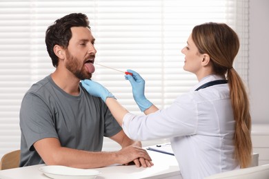 Photo of Doctor taking throat swab sample from man`s oral cavity indoors