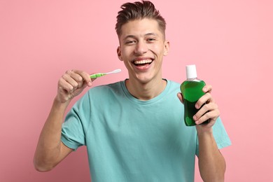 Photo of Young man with mouthwash and toothbrush on pink background