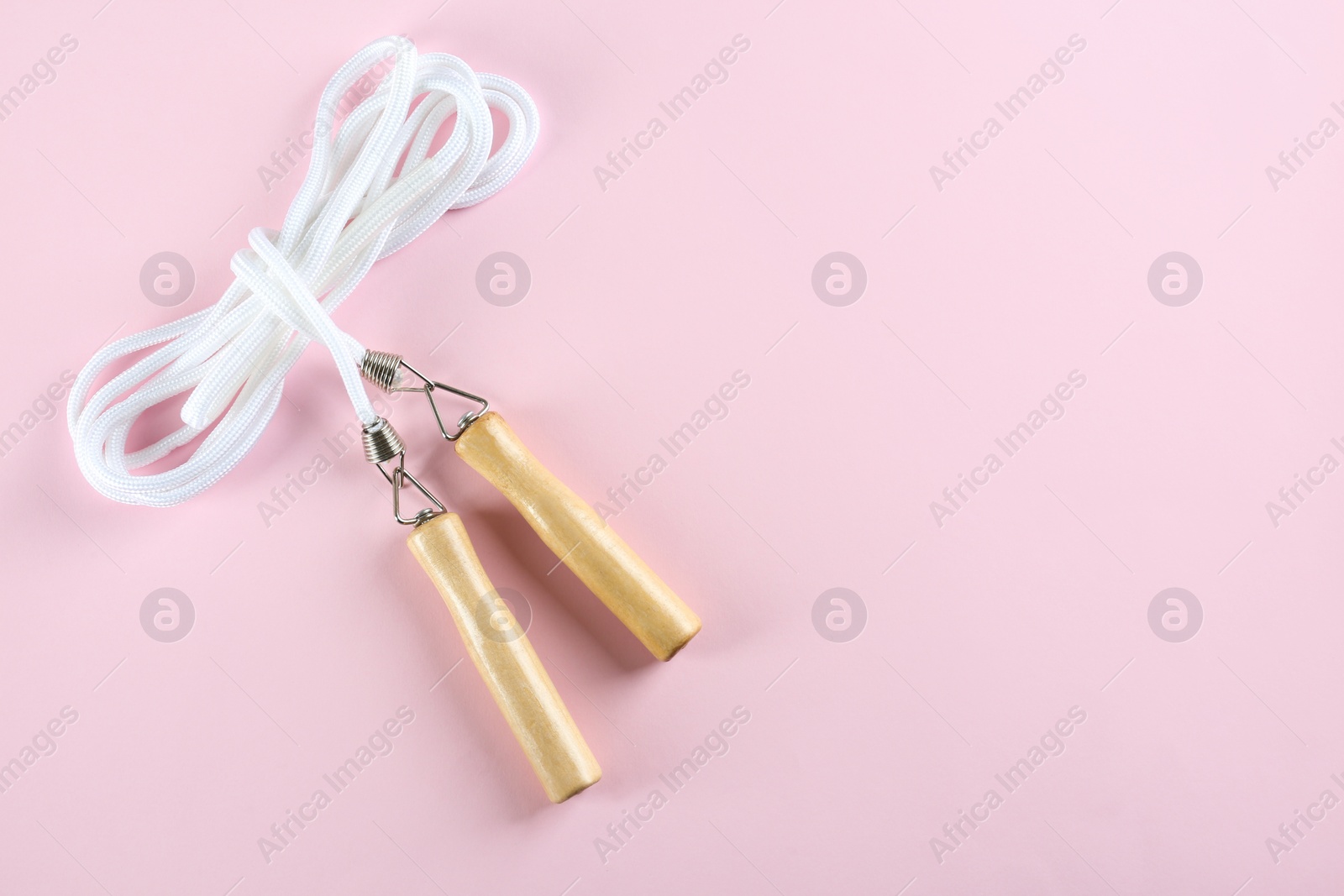 Photo of Skipping rope on pink background, top view. Space for text