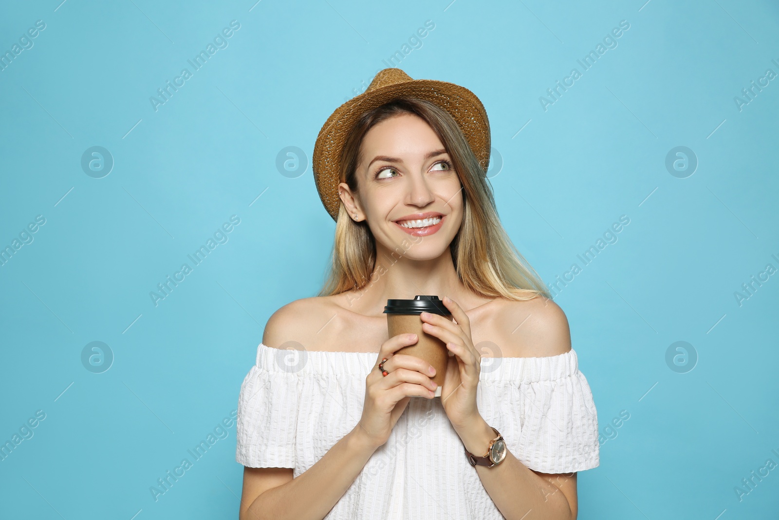 Photo of Beautiful young woman with straw hat and coffee on light blue background. Stylish headdress