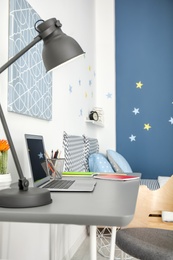 Photo of Comfortable workplace with laptop on desk in modern child room