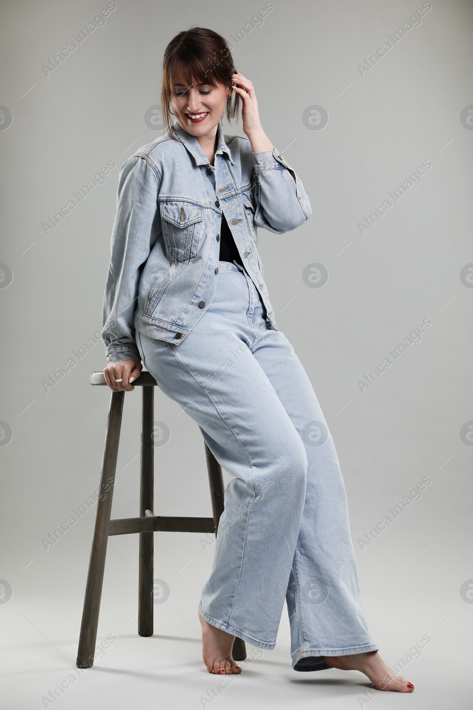 Photo of Beautiful woman sitting on stool against grey background