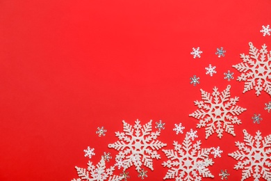 Beautiful decorative snowflakes on red background, flat lay. Space for text