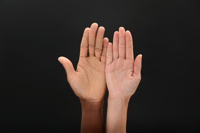 Woman and African American man showing hands on black background, closeup