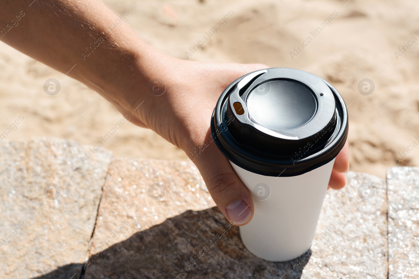 Photo of Woman with takeaway coffee cup on beach, closeup