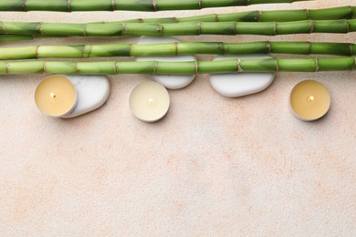 Photo of Spa stones, burning candles and bamboo stems on beige table, flat lay. Space for text