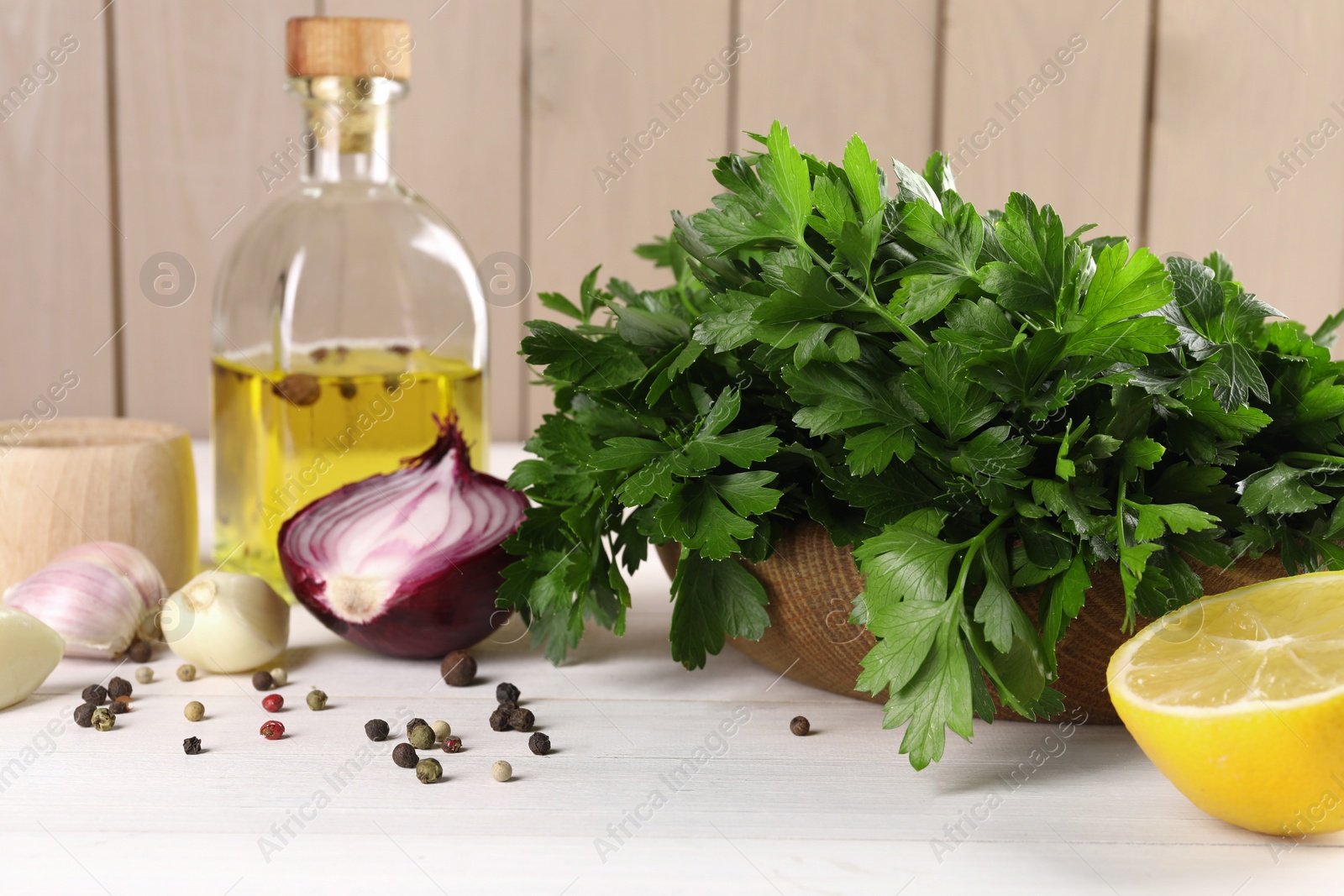 Photo of Fresh green parsley, spices and other products on white wooden table