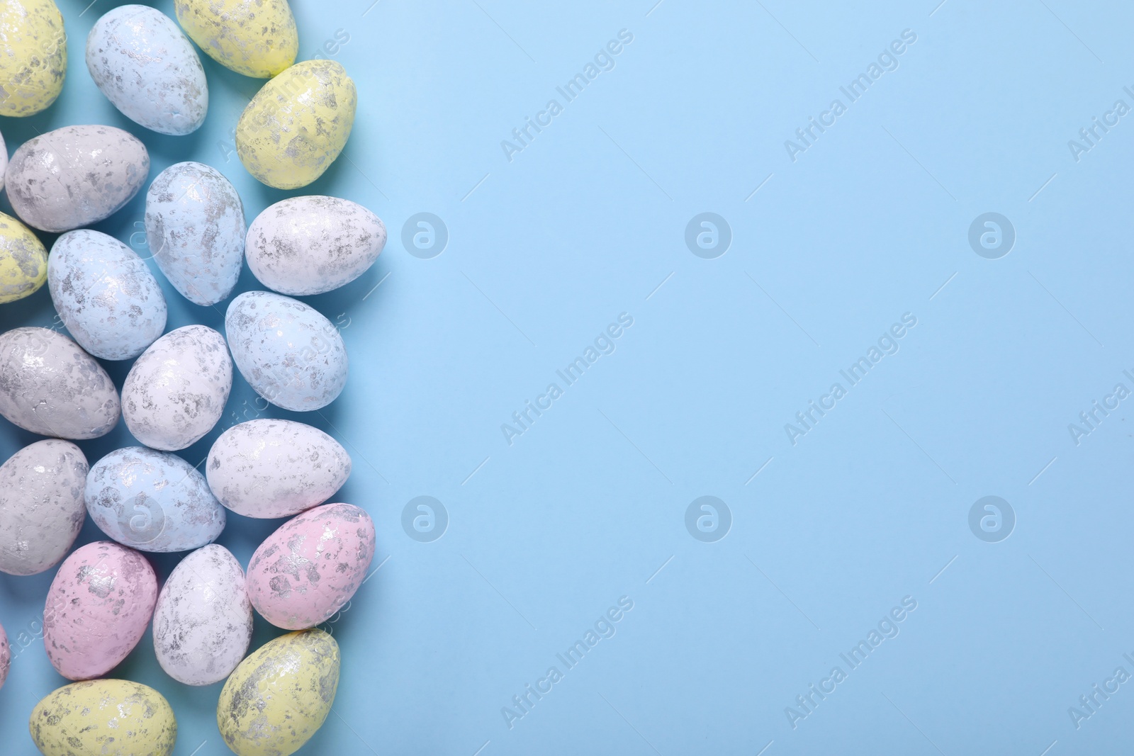 Photo of Many painted Easter eggs on light blue background, flat lay. Space for text