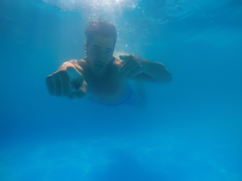 Handsome young man swimming in pool, underwater view