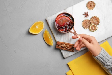 Photo of Woman holding saucepan of hot mulled wine on table, top view with space for text