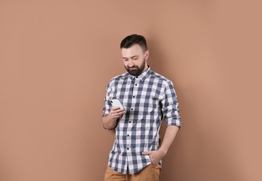 Photo of Portrait of handsome bearded man with mobile phone on color background